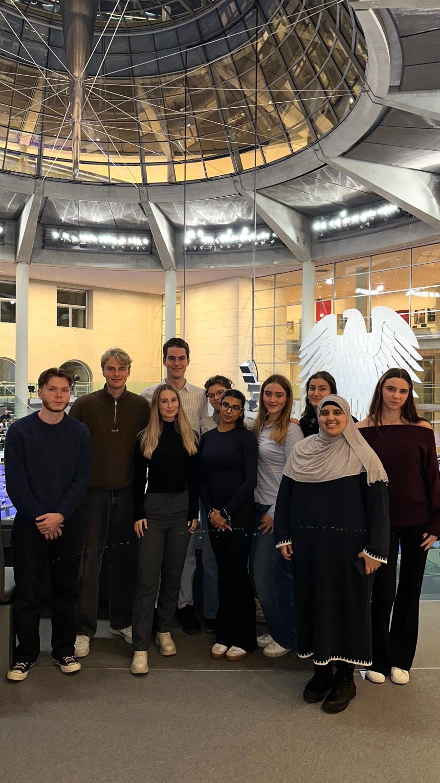 Die Gruppe der peca-Berlin-Exkursion 2025 im Reichstagsgebäude, im Hintergrund der Bundesadler und die Glaskuppel